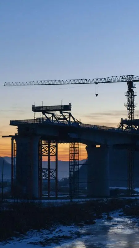 Bridge under construction with a tower crane at dusk